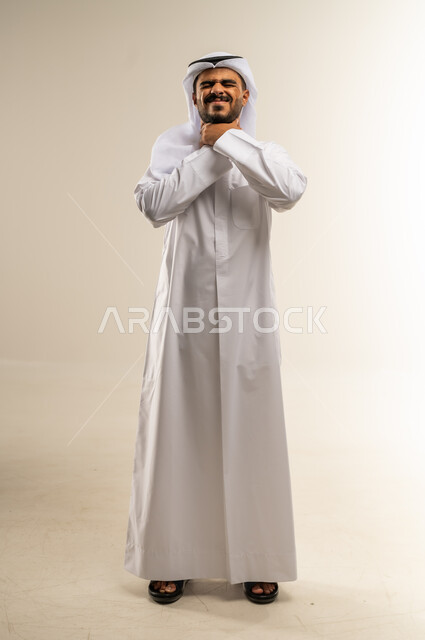 الاحساس بألم البلعوم, الحاجة إلى العلاج والدواء, مفهوم الاهتمام بالصحة, الاصابة بنزلة برد والتهاب الحلق, بورتريه لرجل عربي خليجي كويتي يرتدي الثوب التقليدي ويضع يديه على حلقه ويشعر بالاختناق, صورة الجسم بالطول الكامل، خلفية بيضاء