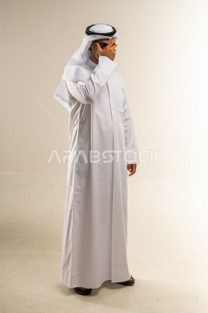 تذكر شيء ما بشكل مفاجئ، الشعور بالخجل والإحراج، محاولة استراق النظر، إغماض العينين وعدم الرغبة بالرؤية، التعرض لصدمة وعدم التصديق، بورتريه لرجل عربي خليجي كويتي يرتدي الثوب التقليدي والغتره يغطي وجهه بيده، الجسم بالطول الكامل، خلفية بيضاء