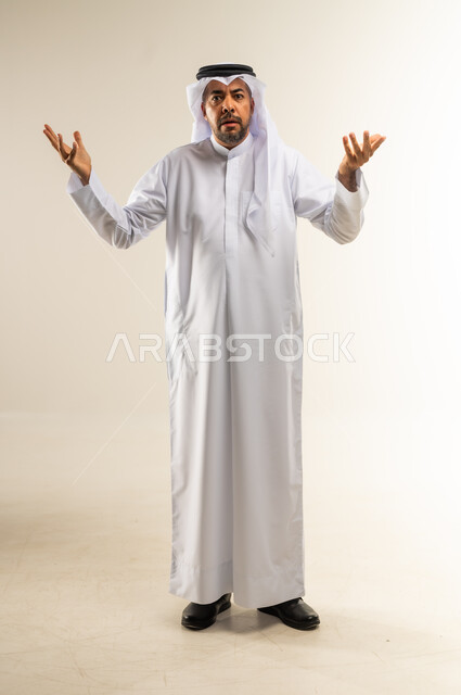 الإستفهام حول موضوع معين, بورتريه  لرجل عربي خليجي كويتي يرتدي الثوب والغترة يرفع يديه نحو الأعلى بإيماءات عدم المعرفة, التساؤل والإستغراب والاستفسار عن أمر ما، الغموض وعدم الوضوح، خلفية بيضاء