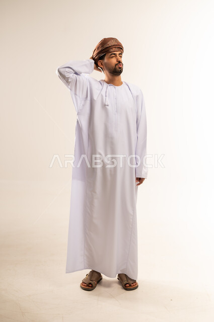 ايماءات تذكر امر ما، الشعور بالدهشة والذهول، النسيان والسهو والغفلة، بورتريه لرجل عربي خليجي كويتي يرتدي الدشداشه والعمامة يضع يده على رأسه بتعابير الصدمة، صورة الجسم بالطول الكامل، خلفية بيضاء