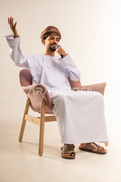 العمل في تقديم الفقرات والبرامج الفنية الترفيهية، إلقاء المحاضرات وإقامة الندوات، تبادل الحوار والاستفادة من الخبرات، بورتريه لشاب عربي خليجي عماني يرتدي الدشداشة والعمامة يحمل بيده المايكروفون يرفع يده بايماءات الاندماج، خلفية بيضاء