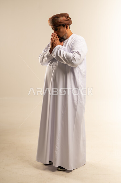 الكحة والإنفلونزا والتهاب الحلق، بورتريه من الجانب لرجل عربي خليجي عماني يرتدي الدشداشة والعمامة يضع يده على فمه بايماءات السعال، الإصابة بنزلة برد، الشعور بالمرض والتعب وصعوبة التنفس، صورة الجسم بالطول الكامل، خلفية بيضاء