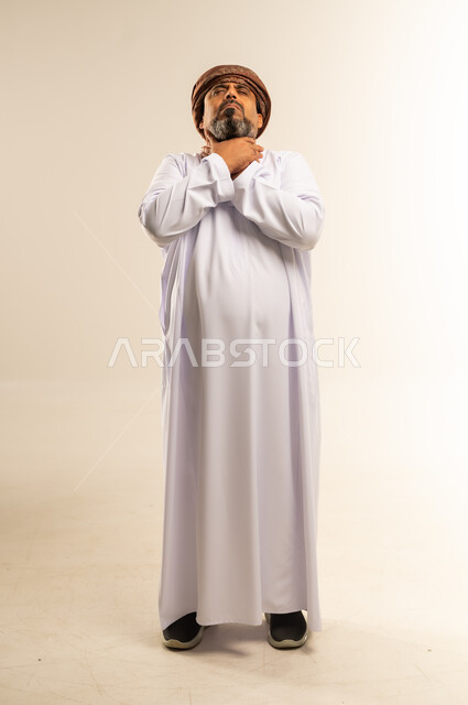 الاختناق والشعور بضيق التنفس، إيماءات الانزعاج الشديد والمعاناة، بورتريه لرجل عربي خليجي عماني يرتدي الدشداشة والعمامة يضع يديه حول عنقه في محاولة لخنق نفسه، قتل النفس للهرب من المشاكل والهموم والضغوطات المحيطة، الجسم بالطول الكامل، خلفية بيضاء