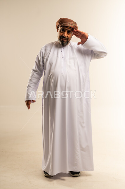 مفهوم الاستقبال والترحيب, التعارف والصداقه وتكوين علاقات, بورتريه لرجل عربي خليجي عماني يرتدي الدشداشة والعمامة يضع يده على رأسه بإيماءات إلقاء التحية والبشاشة، صورة لكامل السم، خلفية بيضاء