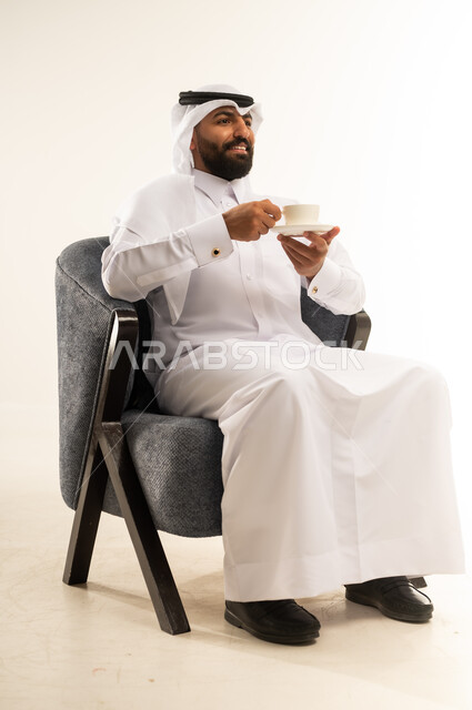 الحيوية والنشاط عند شرب الكافيين، الاستمتاع والاحساس بالدفء عند تناول المشروبات الساخنة، بورتريه لرجل عربي خليجي قطري يرتدي الثوب التقليدي والغترة يحمل بيده كوب القهوة، خلفية بيضاء