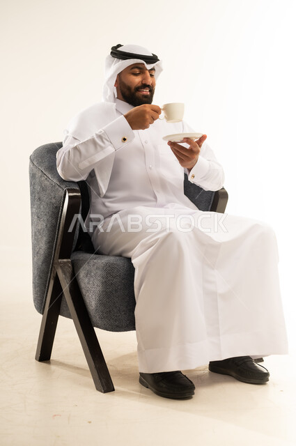 الحيوية والنشاط عند شرب الكافيين، الاستمتاع والاحساس بالدفء عند تناول المشروبات الساخنة، بورتريه لرجل عربي خليجي قطري يرتدي الثوب التقليدي والغترة يحمل بيده كوب القهوة، خلفية بيضاء