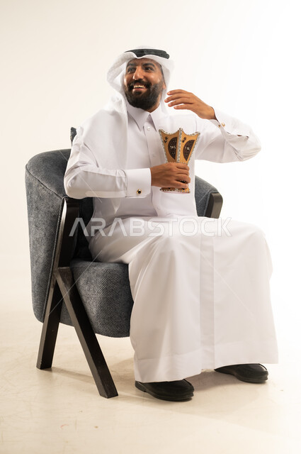 استخدام خشب العود  في الأعياد والمناسبات السعيدة، اتباع العادات والتقاليد العربية الأصيلة، التبخير واستعمال العطور والمطيبات، بورتريه لرجل عربي خليجي قطري يرتدي الثوب التقليدي والغترة يجلس على كرسي ويمسك بيده المبخرة بايماءات الفرح والسرور، خلفية بيضاء