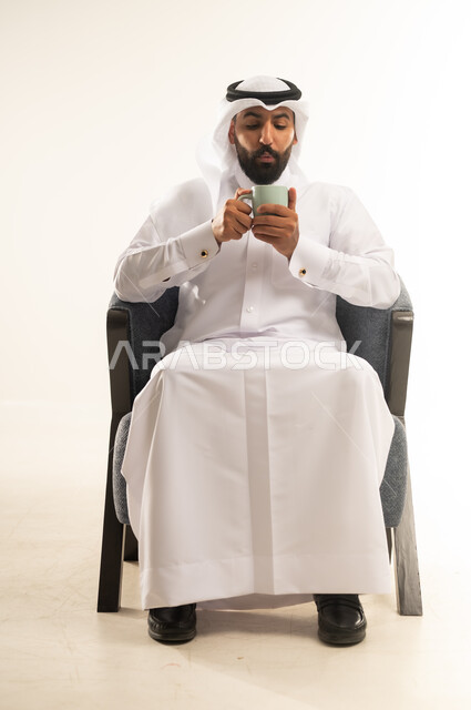 الحيوية والنشاط عند شرب الكافيين، الاستمتاع والاحساس بالدفء عند تناول المشروبات الساخنة، بورتريه لرجل عربي خليجي قطري يرتدي الثوب التقليدي والغترة يحمل بيده كوب القهوة، خلفية بيضاء