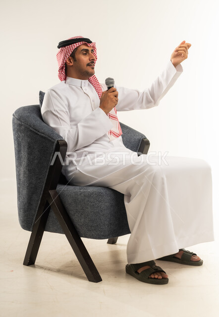 إلقاء الخطابات والكلمات التوعوية، إقامة الندوات وورش العمل والتحاور والنقاش مع الآخرين، تسجيل المقاطع الصوتية والغنائية، بورتريه من الجانب لشاب عربي خليجي بحريني يرتدي الثوب التقليدي والشماغ يجلس على كرسي ويمسك مكبر الصوت بيده، الطول الكامل للجسم، خلفية بيضاء