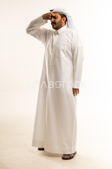 Headache and chronic sinusitis, need for regular checkups and follow-ups, illness, cold and flu, portrait of a Qatari Gulf Arab man wearing traditional thobe and ghutra putting his hand on his nose with an expression of pain, full body image, white background