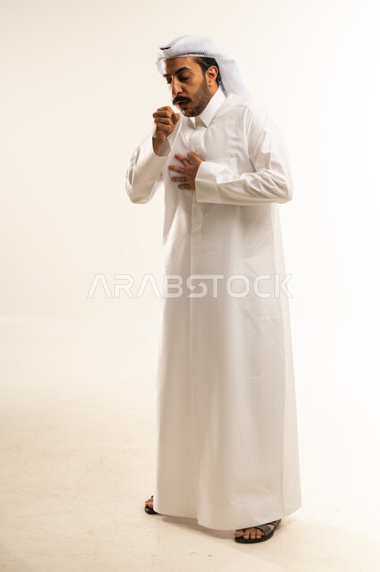 التهاب الأنف التحسسي, الشعور بالمرض و الزكام والحاجة الى العلاج والدواء, بورتريه لشاب عربي خليجي قطري يرتدي الثوب التقليدي والغترة يضع يديه على وجهه بإيماءات العطاس, صوة الجسم بالطول الكامل، خلفية بيضاء
