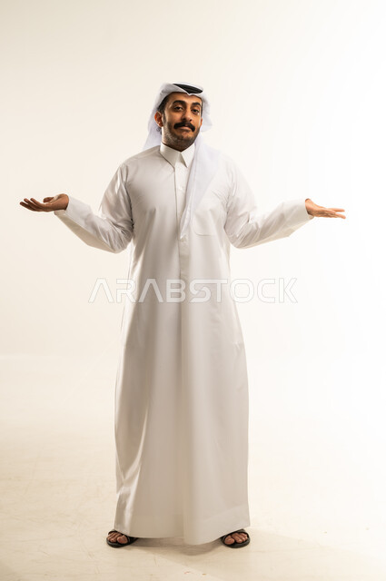 عدم التاكد والقدرة على اتخاذ القرار، التردد بشأن أمر معين، بورتريه لرجل عربي خليجي قطري يرتدي الثوب التقليدي والغترة يرفع كفيه نحو الأعلى بتعابير الحيرة، النظر إلى الكاميرا بإيماءات الاستغراب، صورة الجسم بالطول الكامل، خلفية بيضاء