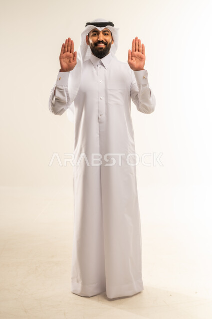 مفهوم الرفض والامتناع والانزعاج, التحذير من فعل شيء ما، طلب التوقف وعدم الاقتراب, بورتريه لرجل عربي خليجي قطري يرتدي الثوب والغترة يمد كفه نحو الأمام بإيماءات النهي عن فعل امر ما, الطول الكامل للجسم، خلفية بيضاء