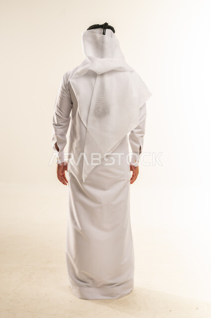 Concern for appearance, concept of elegance and masculinity, portrait from the back of a Qatari Gulf Arab man wearing traditional thobe and ghutra standing straight and upright, full body, white background