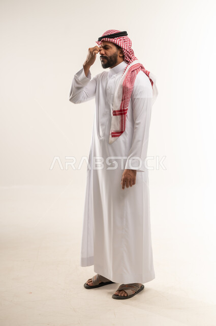 الصداع  وأمراض الجيوب الأنفية المزمنة، شاب سعودي يشعر بالمرض والرشح والانفلونزا, الإحساس بالكسل والخمول، بورتريه من الجانب لرجل عربي خليجي بحريني يرتدي الثوب التقليدي والشماغ يضع يده على انفه بتعابير الكحه والالم، صورة الجسم بالطول الكامل، خلفية بيضاء