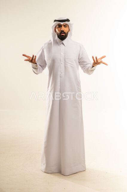 الشعور بالحيرة وعدم المعرفة، بورتريه لرجل عربي خليجي قطري يرتدي الغترة والثوب التقليدي يرفع يفتح كفيه بإيماءات عدم التأكد, التردد وعدم الثقة بخصوص أمر معين، الوقوف باستقامة والنظر إلى الكاميرا، صورة الجسم بالطول الكامل, خلفية بيضاء