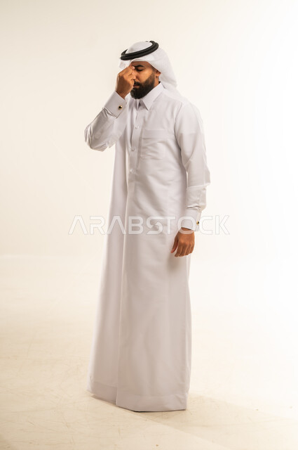 الصداع  وأمراض الجيوب الأنفية المزمنة، الحاجة الي الفحوصات الدورية والمتابعة، المرض والرشح والانفلونزا، بورتريه لرجل عربي خليجي قطري يرتدي الثوب التقليدي والغترة يضع يده على انفه بتعابير الألم، صورة الجسم بالطول الكامل، خلفية بيضاء