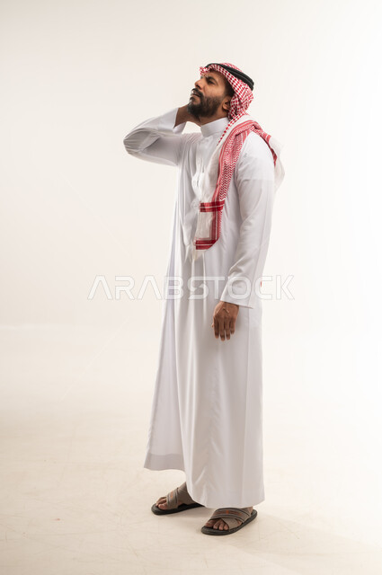 الحاجه للراحة و وضع خطة علاجية, شاب سعودي يشعر بشد عضلي في الرقبه ،التهاب العضلات والمفاصل، الإحساس بالتعب والإرهاق, بورتريه من الجانب لرجل عربي خليجي بحريني يضع يده على رقبته بإيماءات الألم في الأكتاف، صورة الجسم بالكامل، خلفية بيضاء