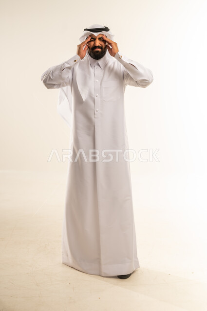 آلام الصداع النصفي، التعرض لنوبات الشقيقة الحادة، الحاجة لتناول المسكنات وأخذ قسط من الراحة، التعرض للتعب والإرهاق والعمل الطويل، بورتريه لرجل عربي خليجي قطري مبتسم يرتدي الثوب التقليدي والغتره يمسك رأسه بيديه بإيماءات الألم، الجسم بالطول الكامل، خلفية بيضاء