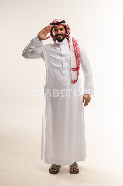 إلقاء التحيه والسلام, مفهوم الاستقبال والترحيب، بورتريه لرجل عربي خليجي بحريني يرتدي الثوب التقليدي والشماغ يرفع يده بايماءات البشاشة، التعارف و الصداقه وتكوين العلاقات, الطول الكامل للجسم، خلفية بيضاء