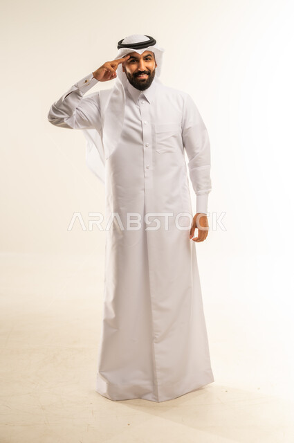 إلقاء التحية والسلام، الأناقة والوسامة والرجولة، مفهوم التقدير والاحترام، بورتريه لرجل عربي خليجي قطري مبتسم يرتدي الثوب التقليدي والغتره ينظر إلى الكاميرا بإيماءات السعادة والسرور، الوقوف باستقامة بتعابير الثقة بالنفس، الجسم بالطول الكامل، خلفية بيضاء