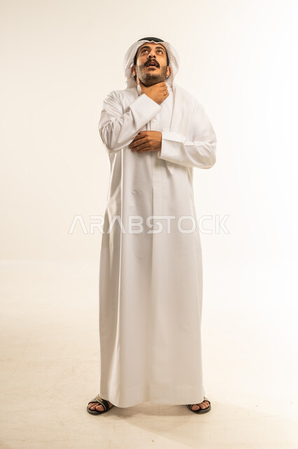 عدم القدرة على التنفس والاحساس بالاختناق، الشعور بآلام في الحلق، أمراض البلعوم والتهاب اللوزتين، بورتريه لرجل عربي خليجي قطري يرتدي الثوب التقليدي والغتره يضع يديه حول عنقه بإيماءات المعاناة والتوجع، الجسم بالطول الكامل، خلفية بيضاء