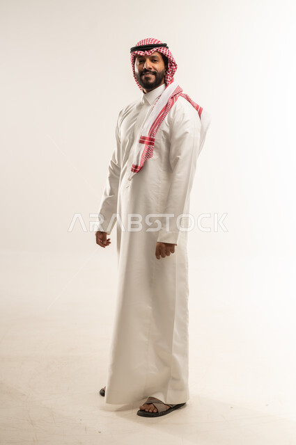 الوقوف باستعداد واستقامة، مفهوم الرجولة والثقة بالنفس، التقاط الصور الشخصية للوثائق الرسمية، بورتريه لرجل عربي خليجي بحريني يرتدي الثوب التقليدي والشماغ ينظر الى الكاميرا بتعابير البشاشة، الأناقة والاهتمام بالمظهر الخارجي، الطول الكامل للجسم، خلفية بيضاء