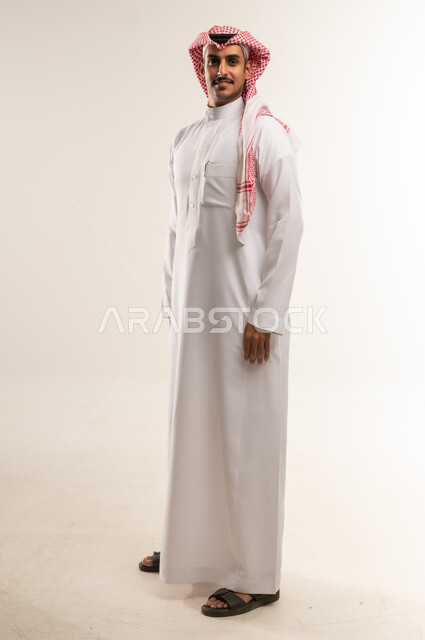 التقاط الصور الشخصية للوثائق الرسمية، بورتريه لشاب عربي خليجي بحريني يرتدي الثوب التقليدي والشماغ ينظر الى الكاميرا بتعابير البشاشة، الأناقة والاهتمام بالمظهر الخارجي، الوقوف باستعداد واستقامة، مفهوم الرجولة والثقة بالنفس، الطول الكامل للجسم، خلفية بيضاء