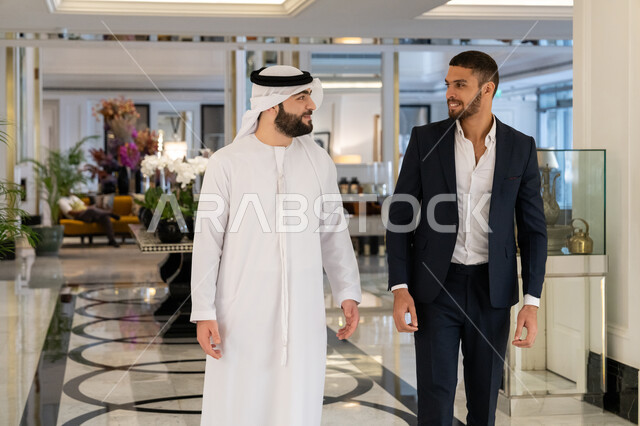 بناء العلاقات الاجتماعية الناجحة, مشاركة الأصدقاء الأوقات الممتعة, التعارف وتكوين الصداقات, الاستمتاع بالجلسات الشبابية في المطعم, رجل عربي خليجي إماراتي يرتدي الكندورة والغترة البيضاء يمشي مع صديقه في إحدى المطاعم بالإمارات