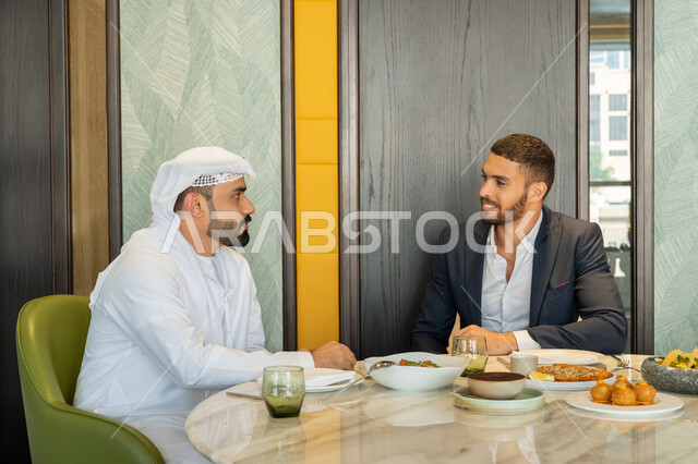 بناء علاقات اجتماعية ناجحة, مشاركة الأصدقاء الأوقات الممتعة, تبادل الأحاديث والاخبار, الاستمتاع بتناول الغداء في المطعم, مجموعة من الأصدقاء العربيين الخليجيين الإماراتيين يجلسون على المائدة في إحدى المطاعم في الإمارات بإيماءات السعادة والسرور