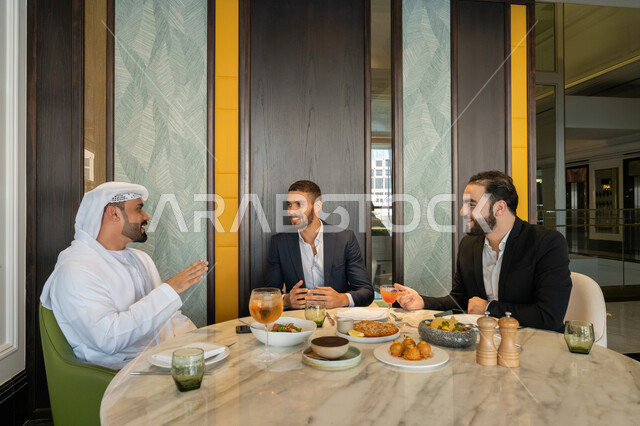 بناء علاقات اجتماعية ناجحة, مشاركة الأصدقاء الأوقات الممتعة, تبادل الأحاديث والاخبار, الاستمتاع بتناول الغداء في المطعم, مجموعة من الأصدقاء العربيين الخليجيين الإماراتيين يجلسون على المائدة في إحدى المطاعم في الإمارات بإيماءات السعادة والسرور