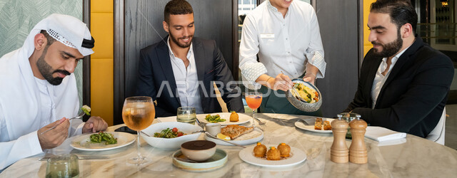 مشاركة الأصدقاء الأوقات الممتعة, تبادل الأحاديث والاخبار, الاستمتاع بتناول الغداء في المطعم, بناء علاقات اجتماعية ناجحة, صورة مقربة لمجموعة من الأصدقاء العربيين الخليجيين الإماراتيين يجلسون على المائدة في إحدى المطاعم في الإمارات ويقومون بتناول الطعام