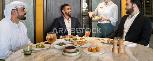 مشاركة الأصدقاء الأوقات الممتعة, تبادل الأحاديث والاخبار, الاستمتاع بتناول الغداء في المطعم, بناء علاقات اجتماعية ناجحة, صورة مقربة لمجموعة من الأصدقاء العربيين الخليجيين الإماراتيين يجلسون على المائدة في إحدى المطاعم في الإمارات ويقومون بتناول الطعام
