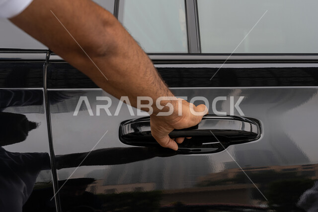 خدمات النقل الآمنة والمريحة, خدمة صف السيارات في الإمارات العربية المتحدة, توصيل الركاب للوجهة المطلوبة, صورة مقربة ليد رجل عربي خليجي إماراتي يرتدي الزي الخاص بالعمل يقوم بفتح باب السيارة
