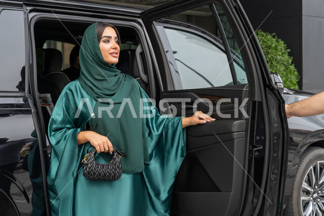خدمة توصيل الزبائن في الإمارات العربية المتحدة, الوصول للوجهة المطلوبة، خدمات النقل الامنة, امرأة عربية خليجية إماراتية ترتدي العباءة الملونة تخرج من السيارة, شابة سعودية تستخدم التاكسي