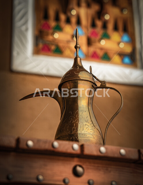 مفهوم الكرم وحسن الاستقبال، ذكرى تأسيس الدولة السعودية الاولى 22 فبراير، يوم بدينا 1727 م، الاحتفال بالمناسبات والأعياد الوطنية، تقديم المنتجات المحلية للضيوف، صورة مقربة لدلة قهوة نحاسية على طاولة خشبية 