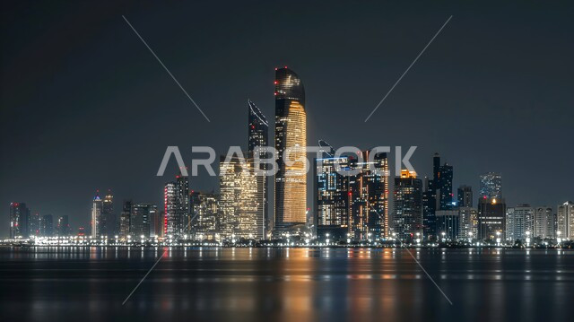 النمو والتقدم العمراني للابراج وناطحات السحاب، الفن الهندسي المعماري المتطور للمنشآت التجارية والسكنية، المباني والمنتجعات الفاخرة في ابو ظبي بالإمارات العربية المتحدة في وقت الليل، المدن السياحية الساحلية 