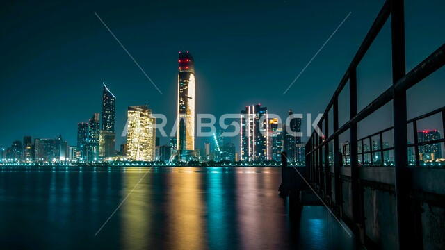 النمو والتقدم العمراني للابراج وناطحات السحاب، الفن الهندسي المعماري المتطور للمنشآت التجارية والسكنية، المباني والمنتجعات الفاخرة في ابو ظبي بالإمارات العربية المتحدة في وقت الليل، المدن السياحية الساحلية