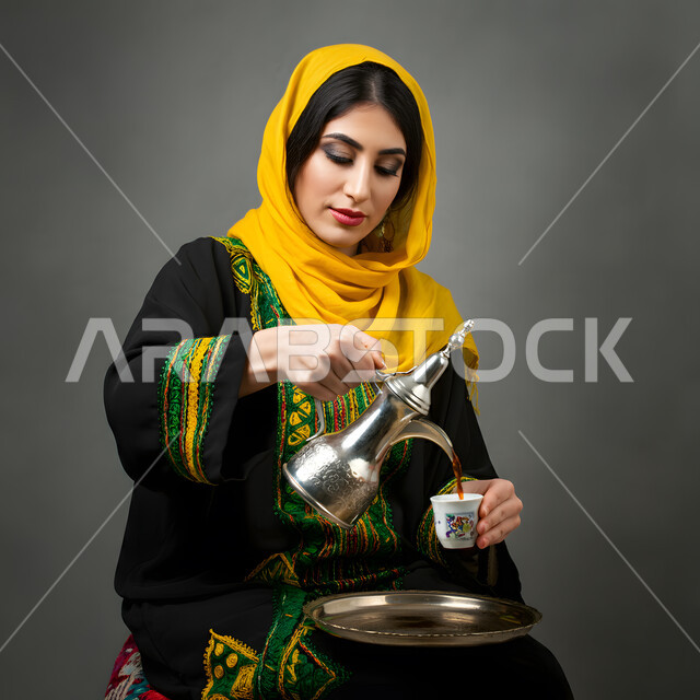 العادات والتقاليد الأصيلة، تقديم المشروبات الساخنة، حسن الضيافة والاستقبال عند العرب، مفهوم الأنوثة والنعومة، الاهتمام بالمظهر الخارجي، بورتريه لامرأة عربية خليجية سعودية ترتدي العباءة السوداء تقوم بصب القهوة في فنجان، خلفية رمادية