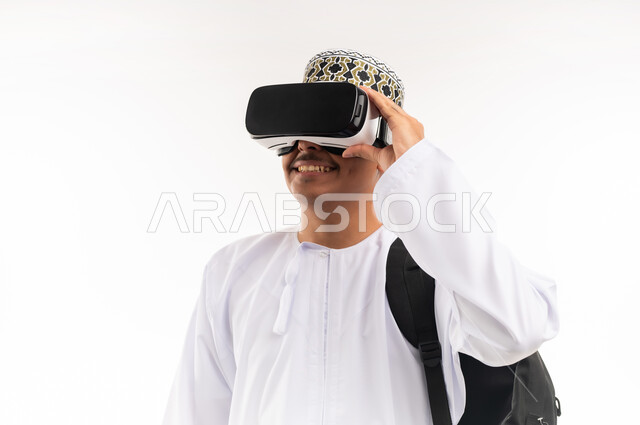 Integration and interaction with the imaginary world, use of advanced techniques and technology, portrait of a young Arab Gulf Omani man wearing a dishdasha and an Omani kummah, wearing VR glasses on his eyes, watching virtual reality movies, spending leisure time in a fun way, white background