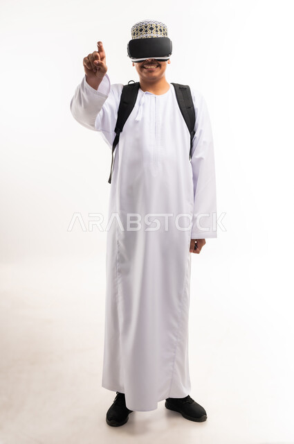 Spending free time watching virtual reality movies, clicking on the screen and trying to touch an item, interacting and simulating the imaginary world, portrait of a young Arab Gulf Omani man wearing a dishdasha and a kimono, wearing 3D glasses, full-length body image, white background
