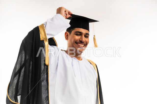 التعليم الاكاديمي في جامعات سلطنة عمان, مشاعر السرور والسعادة بتحقيق حلم النجاح, مفهوم الدراسة والنجاح والتفوق, بورتريه مقرب لخريج جامعي عربي خليجي عماني يرتدي العباءة وقبعة التخرج ينظر إلى الكاميرا بابتسامة, خلفية بيضاء