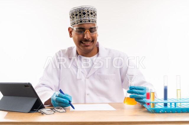 التعليم الاكاديمي في سلطنة عمان, التفاعلات الكيميائية داخل المختبر, اجراء التجارب العلمية, اسخدام انابيب الاختبار الزجاجية, دمج التعليم مع التقنية والتكنولوجيا, بورتريه مقرب لطالب جامعي عربي خليجي عماني يرتدي الكمه والدشداشه يجلس في معمل الكيمياء, خلفية بيضاء