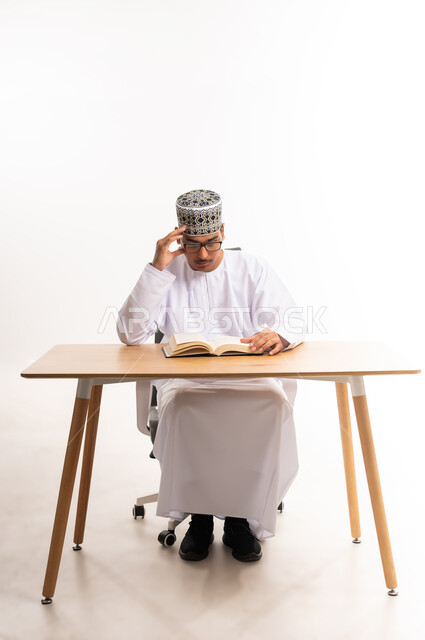 المناهج والمواد التعليمية في سلطنة عمان, الاستمتاع بممارسة هواية المطالعة, بورتريه لطالب جامعي عربي خليجي عماني يرتدي الدشداشه والكمه والنظارة الطبية يقوم بقراءة الكتاب, قضاء أوقات الفراغ بالأنشطة المفيدة, مفهوم التعلم والتفوق والاجتهاد, خلفية بيضاء