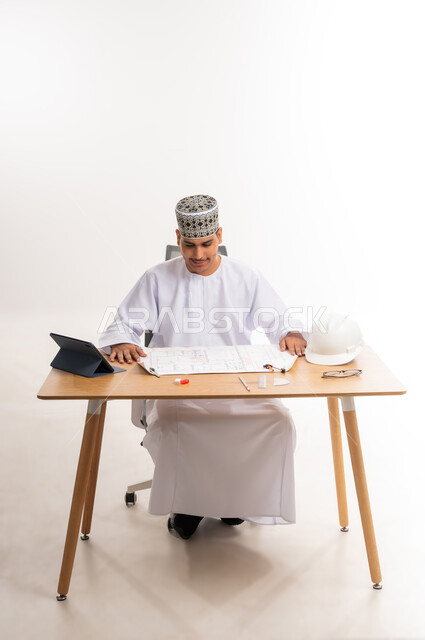 دمج التكنولوجيا في المجال التعليمي, الدراسة و الاجتهاد والتفوق, المناهج والمواد التعليمية، التعليم الجامعي في سلطنة عمان, بورتريه لطالب جامعي عربي خليجي عماني يرتدي الكمه والدشداشه يقوم بدراسة وتصميم المشروع الهندسي, مفهوم الهندسة والانشاء، خلفية بيضاء