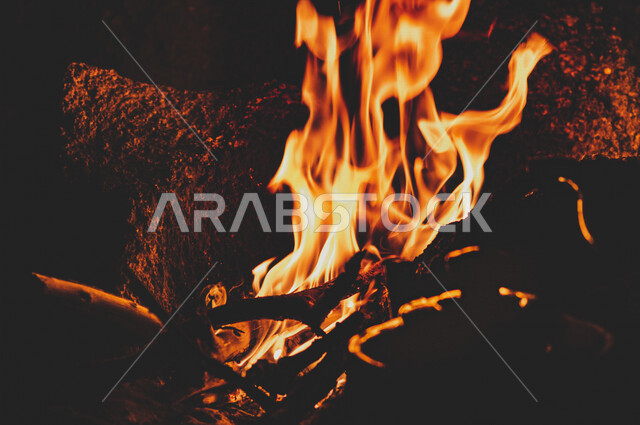 النيران المشتعلة  في الحطب ، اللهب الأحمر المشتعل في رحلة تخييم بالصحراء ، جمال الطبيعة في صحراء المملكة العربية السعودية ليلاً