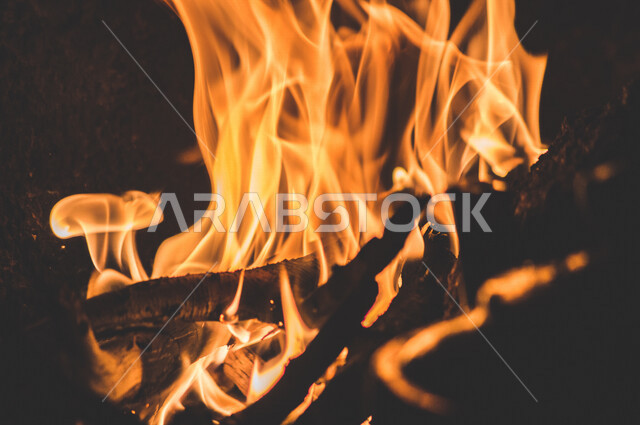 النيران المشتعلة  في الحطب ، اللهب الأحمر المشتعل في رحلة تخييم بالصحراء ، جمال الطبيعة في صحراء المملكة العربية السعودية ليلاً