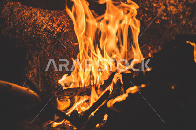 النيران المشتعلة  في الحطب ، اللهب الأحمر المشتعل في رحلة تخييم بالصحراء ، جمال الطبيعة في صحراء المملكة العربية السعودية ليلاً