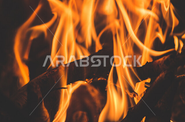 النيران المشتعلة  في الحطب ، اللهب الأحمر المشتعل في رحلة تخييم بالصحراء ، جمال الطبيعة في صحراء المملكة العربية السعودية ليلاً