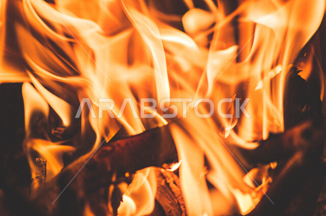 النيران المشتعلة  في الحطب ، اللهب الأحمر المشتعل في رحلة تخييم بالصحراء ، جمال الطبيعة في صحراء المملكة العربية السعودية ليلاً